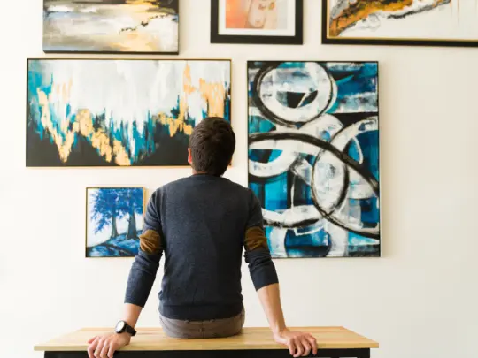 Rear view of a guy in his 30s looking at an art exhibition